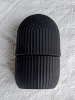 Black face ice roller placed on a textured grey cloth, showing its sleek design.