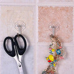Pair of small stainless steel adhesive hooks on a white wall.