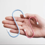 A hand holding a blue and a pink plastic coated S hook, showing their size.