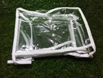 A clear plastic and white fabric organizer, folded flat, rests on a textured green surface.