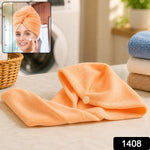 A woman in a white tank top is bending over to put on a long, light purple microfiber hair towel.