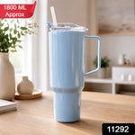A light blue travel tumbler with a handle and straw sits on a wooden table, with