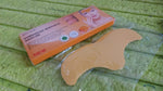 An orange box of forehead wrinkle patches next to a single gold patch in clear packaging on a green textured surface.