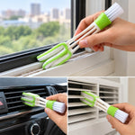 A hand holding a white and green 3-in-1 cleaning brush, using the microfiber side to clean a window sill.
