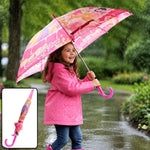 A young girl in a pink raincoat holds an open pink Disney Princess umbrella in the rain.