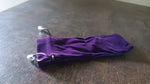 A purple velvet drawstring bag with a DayShow logo lies on a dark brown wooden surface.
