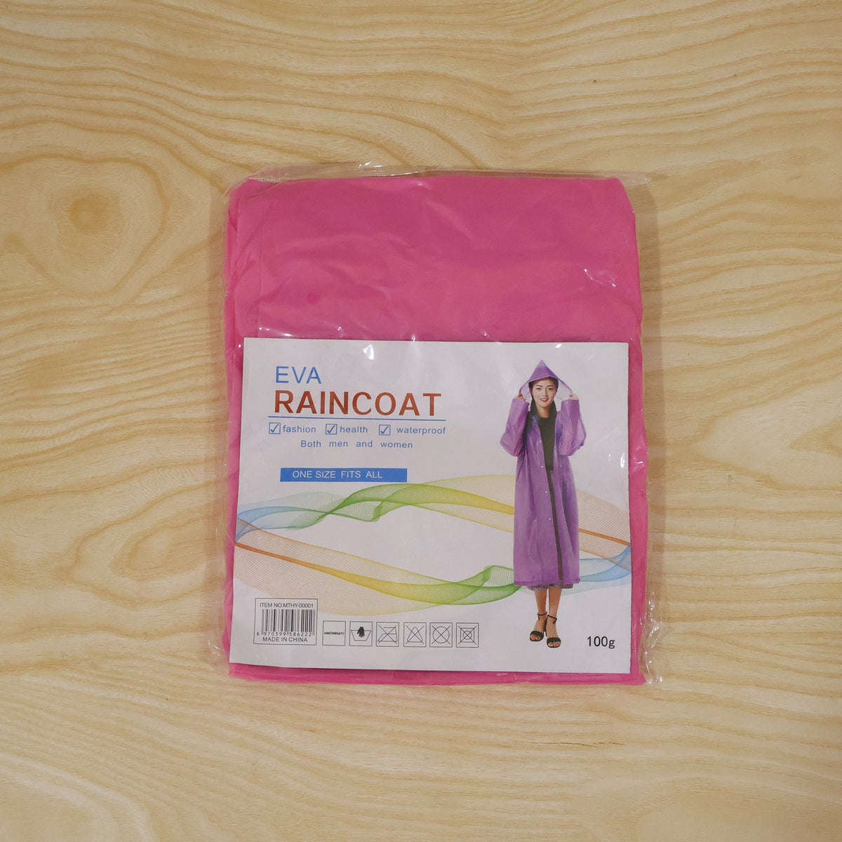 A folded pink EVA raincoat in clear plastic packaging with product information and an image of a person wearing a purple