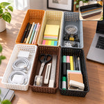 Six rectangular plastic baskets in various colors filled with office supplies on a wooden desk.