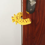 A yellow giraffe-shaped EVA door stopper is shown from a different angle, wedged on a brown door.