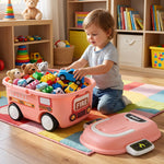 A toddler sits on a colorful rug, placing a blue car toy into the pink fire truck storage box filled with other toys.