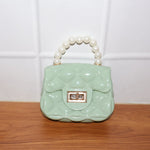 Model carrying an elegant quilted mini handbag with pearl handle and chain strap