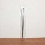 Stainless steel chopsticks actively used to pick up food during a meal.