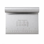 A close-up of a stainless steel dough scraper with a ruler on the bottom edge and a measurement conversion chart on the