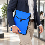 A person in business attire walking while holding a blue plastic document folder with a black elastic closure.