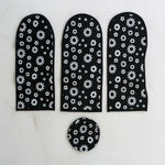 Three long black and white floral dust covers and one round cover arranged on a white marble surface.