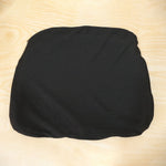 A black fabric cover for a seat cushion, laid flat on a light wooden surface.