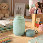 A mint green glass bottle with a bunny print sits on a desk, with a matching lid beside it. A girl drinks from the bottle in
