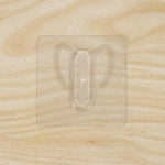 Close-up of transparent wall hook showing its adhesive pad