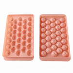 Two pink plastic ice ball trays, one with open spherical molds and the other with covered molds.