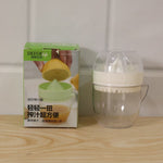 A boxed citrus juicer next to the actual white and clear plastic manual citrus squeezer on a wooden surface.