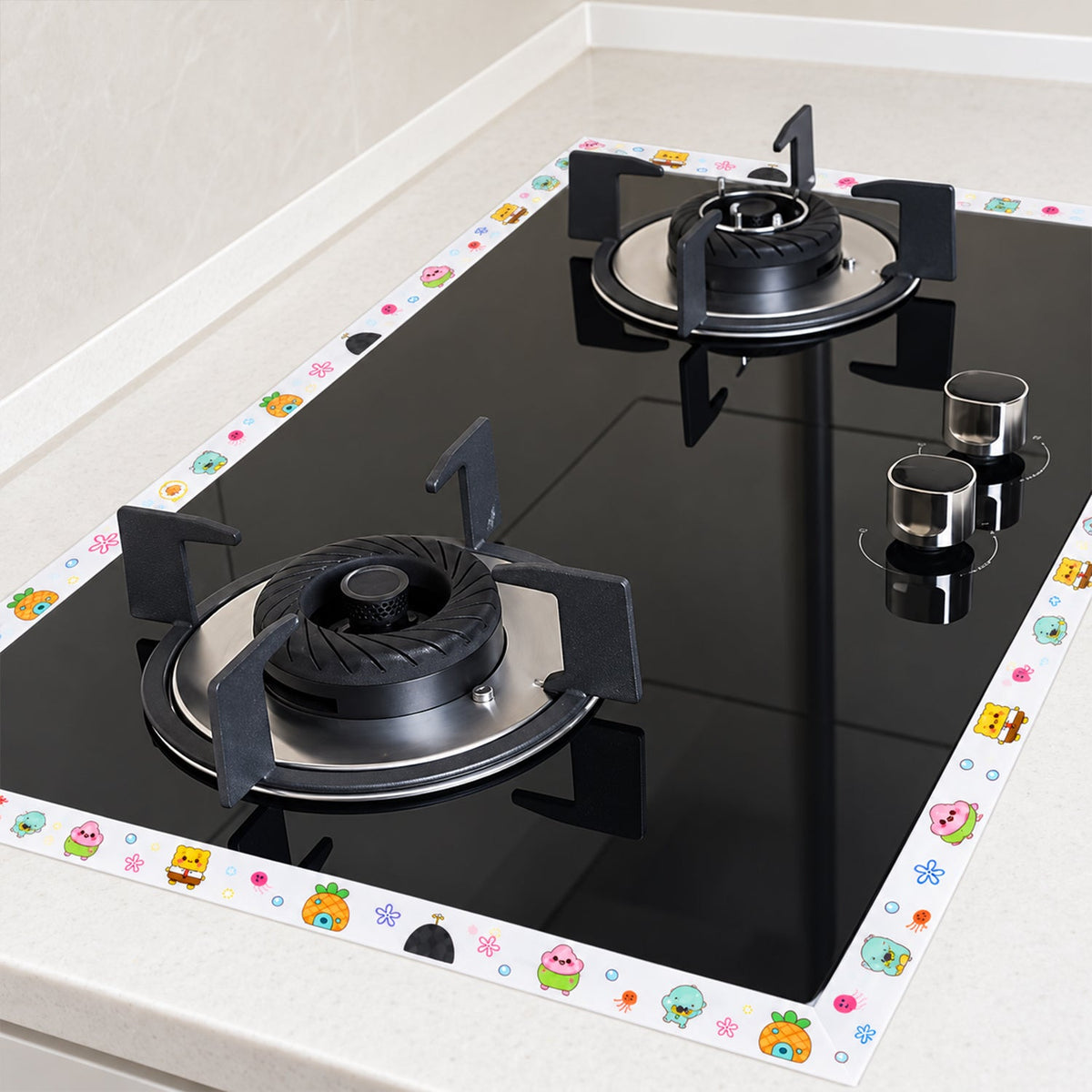 The cartoon-printed sealing tape borders a black gas cooktop on a white kitchen counter.