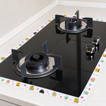 The cartoon-printed sealing tape borders a black gas cooktop on a white kitchen counter.