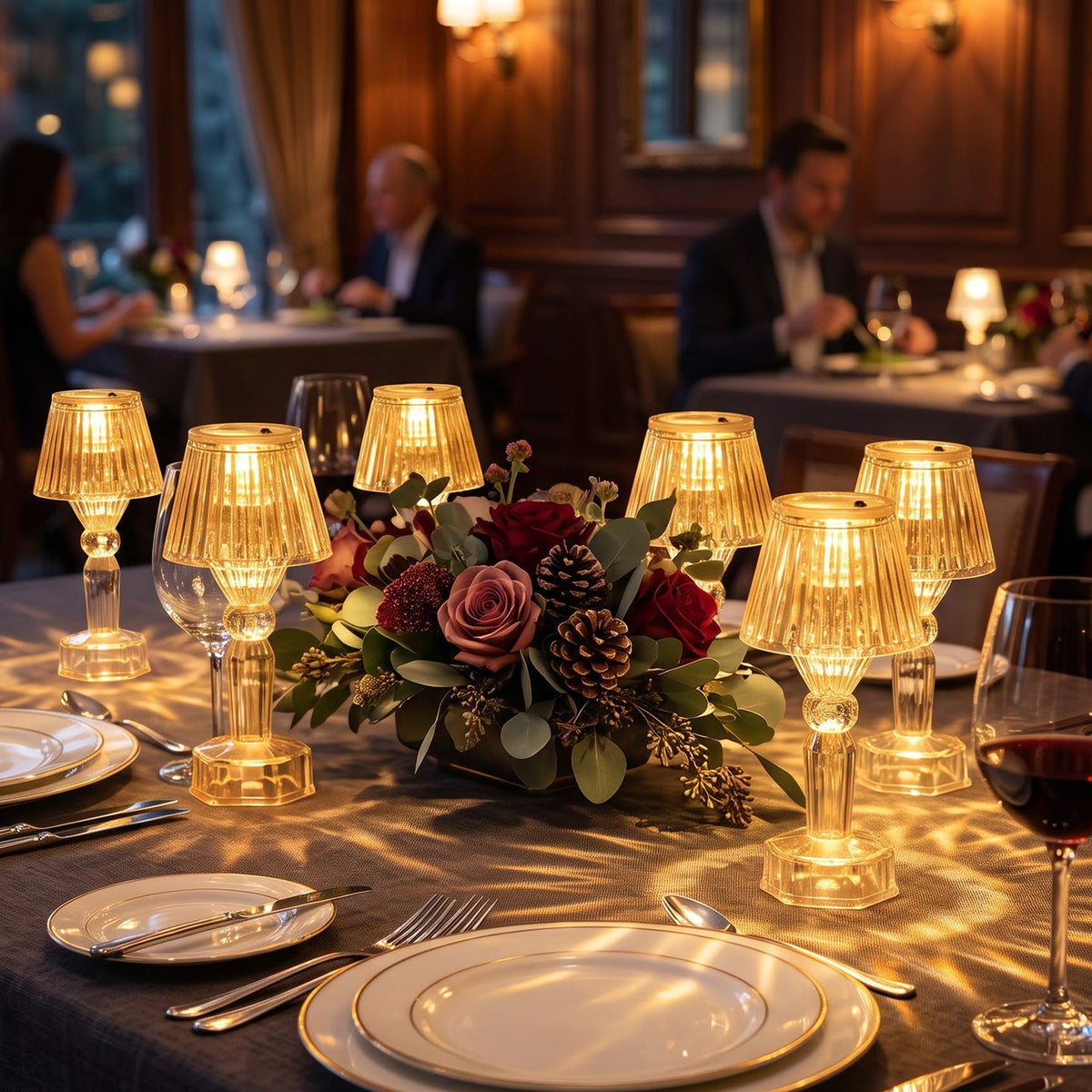 A restaurant dining table is set with multiple glowing clear acrylic LED lamps, casting patterns on the dark tablecloth.