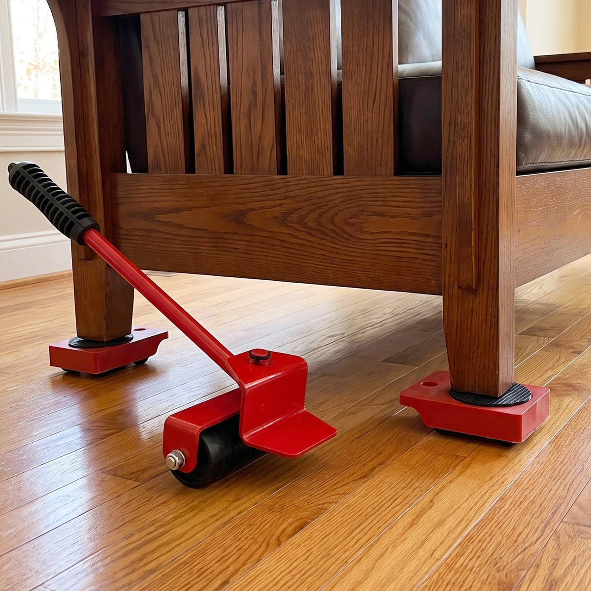 A red furniture lifter tool is shown under a wooden chair leg, with three red wheeled sliders already in place.