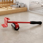 A red furniture lifter tool with a black handle and rollers rests on a light grey workbench with tools in the background.