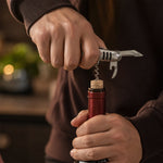 A hand uses the silver multi-tool's screwdriver to tighten a bolt on a bicycle fender.