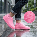 A person wears pink silicone shoe covers on a wet sidewalk; a circular inset shows a close-up of the zigzag tread pattern on