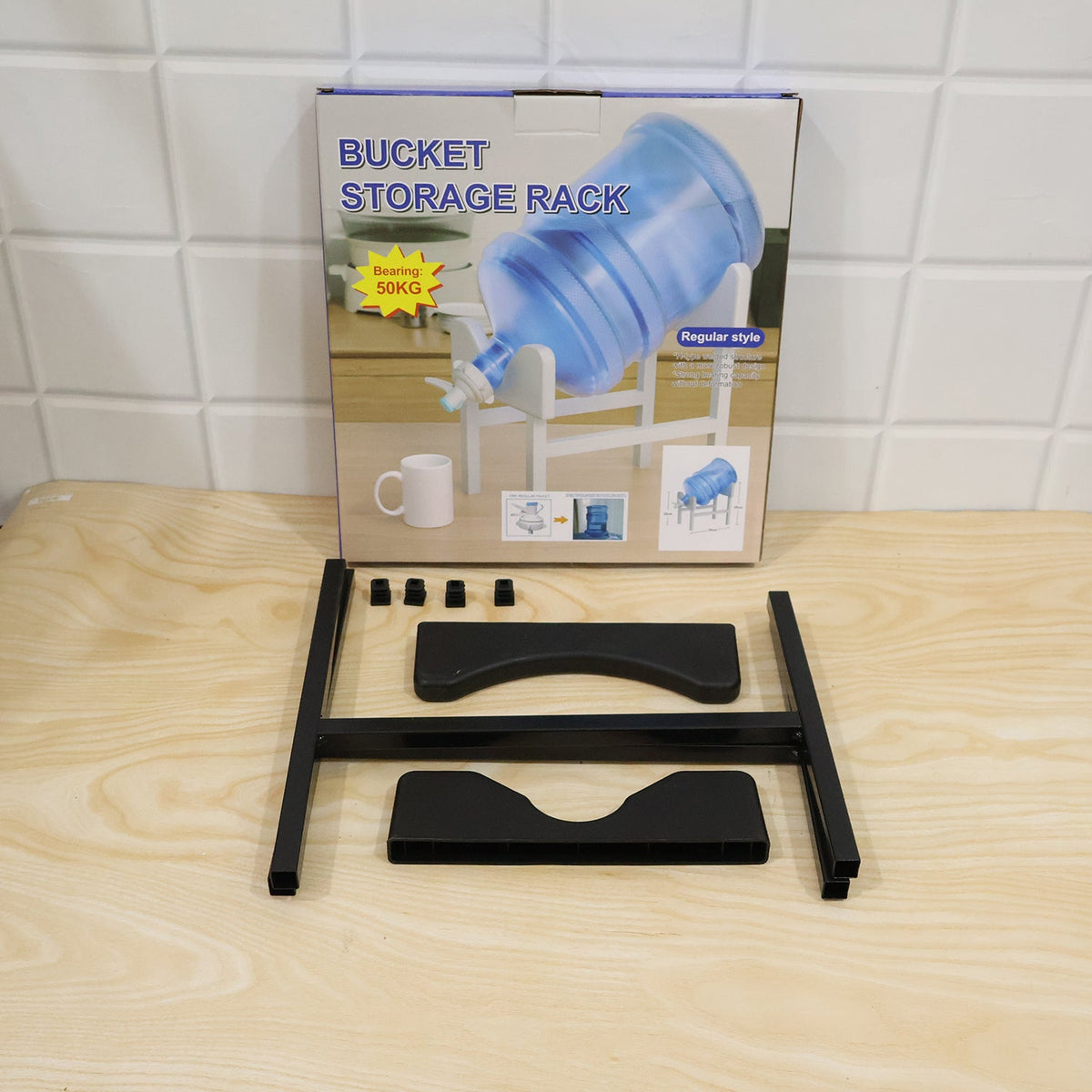 A disassembled black metal water bottle stand and its packaging box are displayed on a light wooden surface.