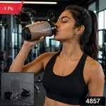 A woman in a black sports bra drinks from a grey and black shaker bottle in a gym, with a red "1 Pc" label and a black