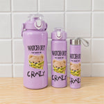 Three purple water bottles with a teddy bear design, in varying sizes, on a wooden surface against a white tiled wall.