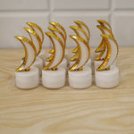 Eight golden crescent moon LED tealights in clear plastic packaging on a light wooden surface.