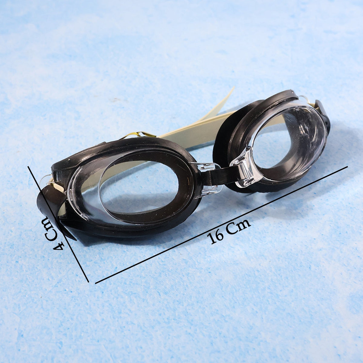 Black and clear swimming goggles with a beige strap on a blue background, showing dimensions of 16 cm and 4 cm.