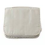 A neatly folded rectangular beige toiletry bag with a handle on a plain white background.