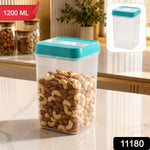 A clear plastic storage container with a teal lid, filled with cashews and almonds, on a kitchen counter with a red 1200 ML