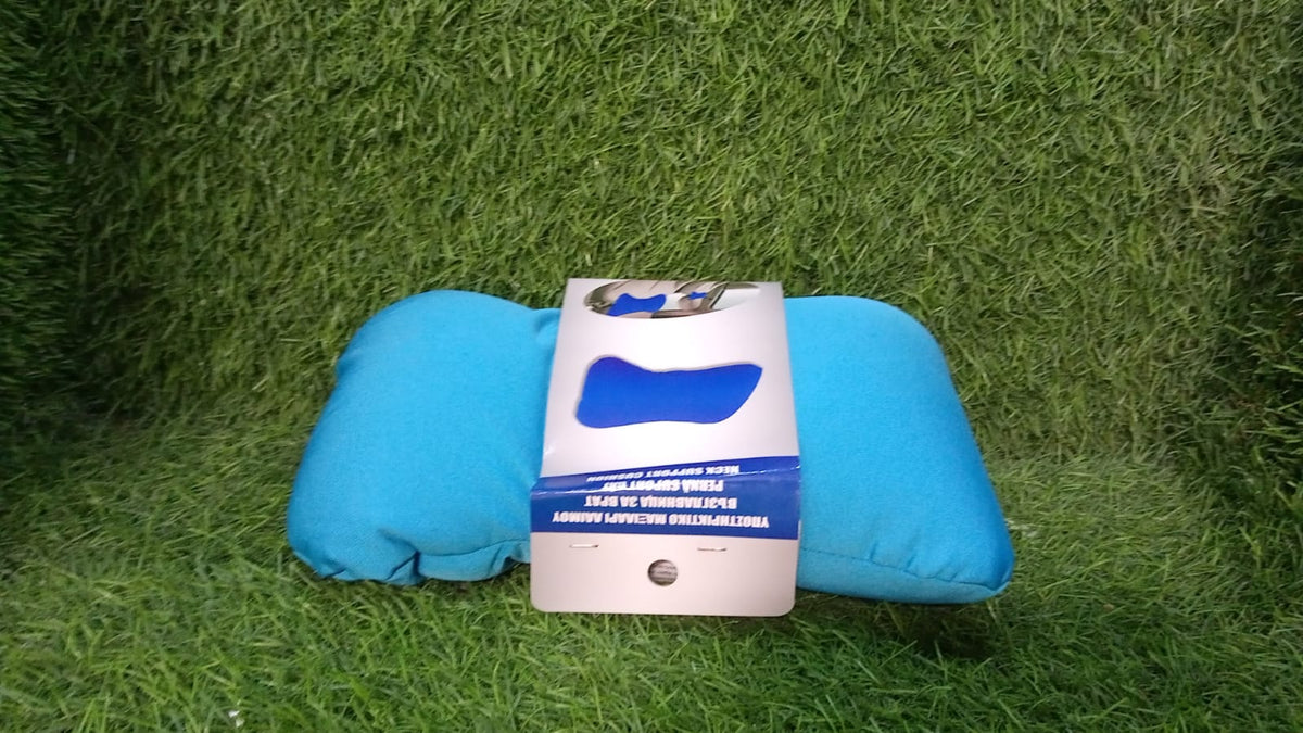 A bright blue bone-shaped pillow lying on green grass, with a white and blue product label placed on top of it.