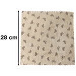 A beige microfiber towel with a dark bow pattern and scalloped edges lies flat on a white background, with a 28 cm