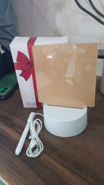 The lamp components, including a white base, USB cable, marker, and brown acrylic board, next to a white gift box with a red