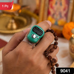 A hand holds a green digital tally counter on a finger, with brown prayer beads. A red "1 Pc" label is in the top left