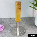 A stainless steel masher with a light brown wooden handle stands upright on a gray speckled counter next to a green plant.