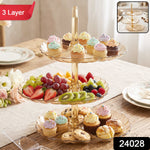 A three-layer amber acrylic dessert stand displays various treats, fruit, and baked goods on a dining table.