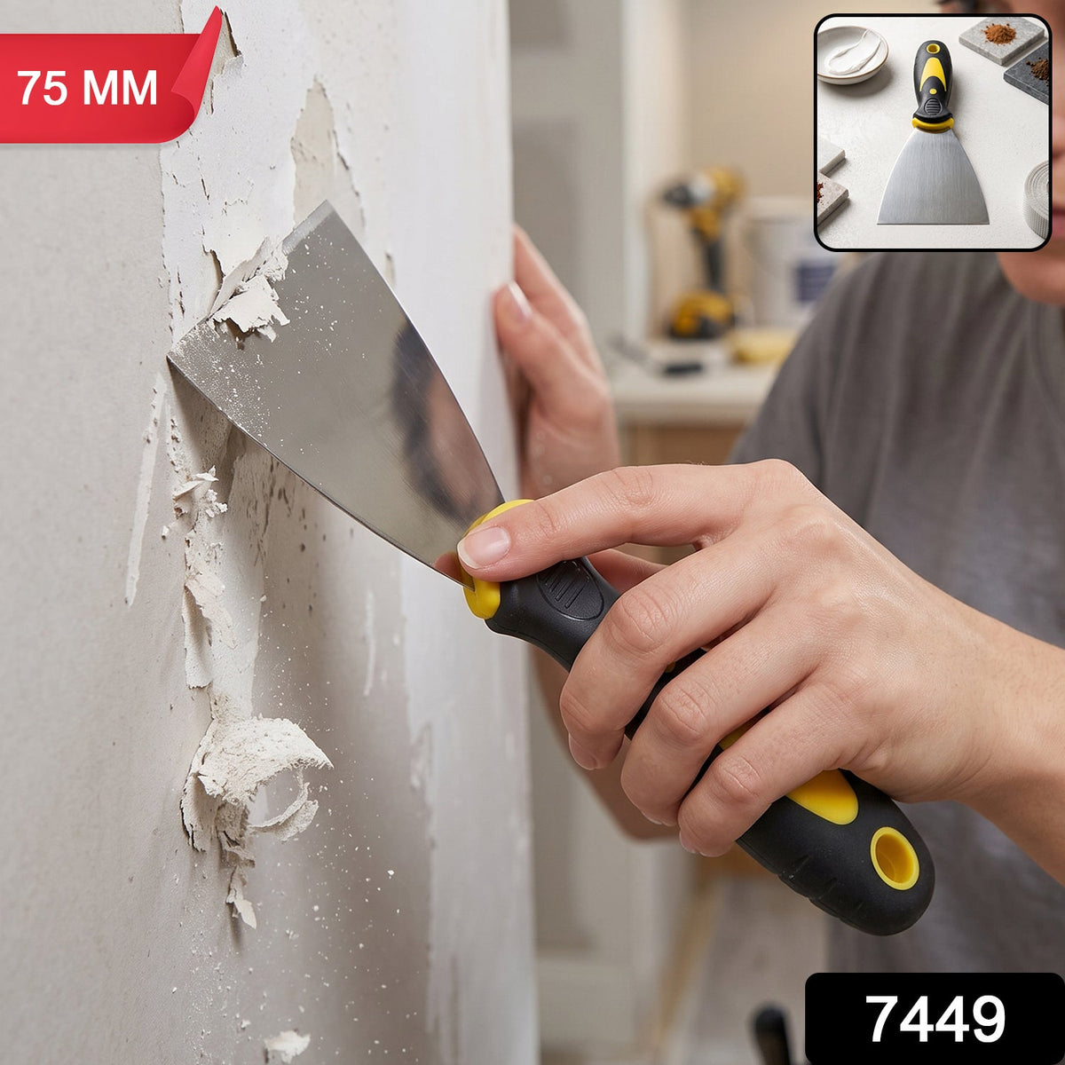 A person's hands using a black and yellow handled 75mm putty knife to scrape peeling paint off a light-colored wall.