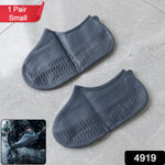 A pair of gray silicone foot coverings with textured soles on a tiled floor, with a red