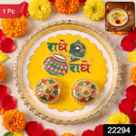 A silver and yellow Radhe Radhe pooja thali set with two small decorative containers, surrounded by marigolds and rose,