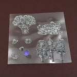 A clear rubber stamp sheet features detailed designs of a tree, bird's nest, and multiple birdhouses.