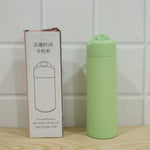 A light green glass water bottle with a silicone sleeve next to its white packaging box with Chinese text and