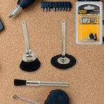 Three black nylon brushes, two with silver shafts, are laid out on a cork surface next to a tape measure and drill bits